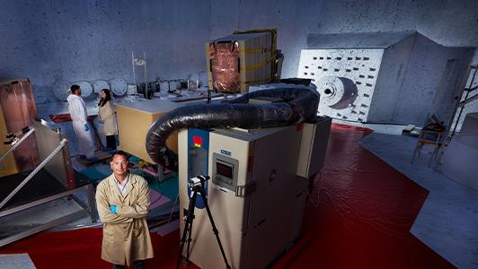 Scientist standing next to large equipment with view ports